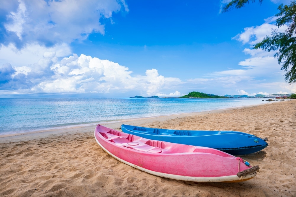เรือแคนูสีชมพูและสีฟ้าสองลำพักผ่อนบนหาดทรายในราชบุรีที่เที่ยว ที่พักผ่อนสัตหีบ
