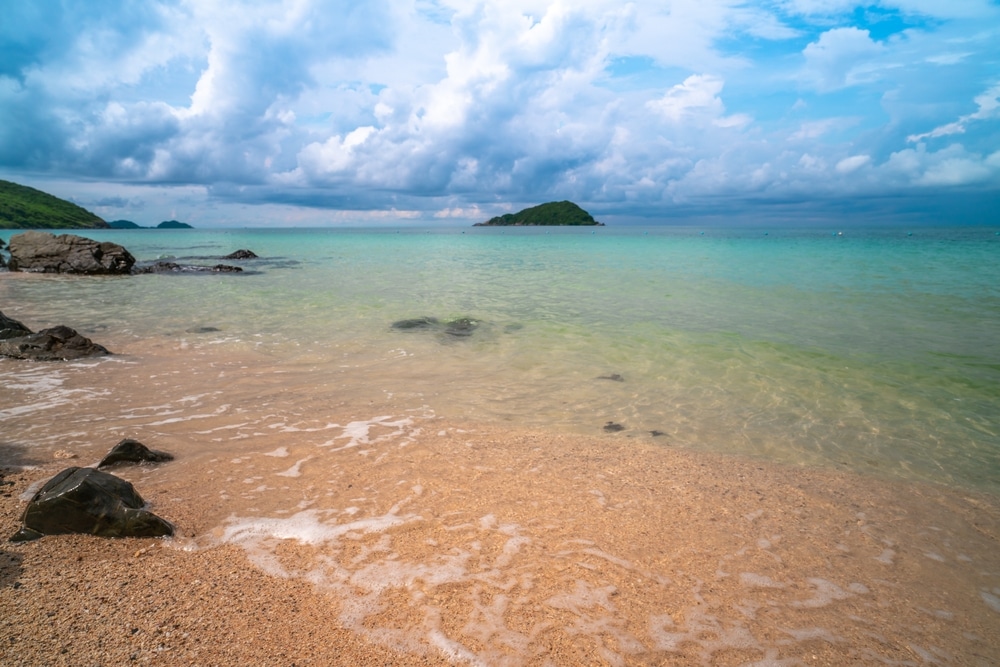 ชายหาดที่มีหินและน้ำในเที่ยวราชบุรีภายใต้ท้องฟ้าที่มีเมฆมาก ที่พักผ่อนสัตหีบ