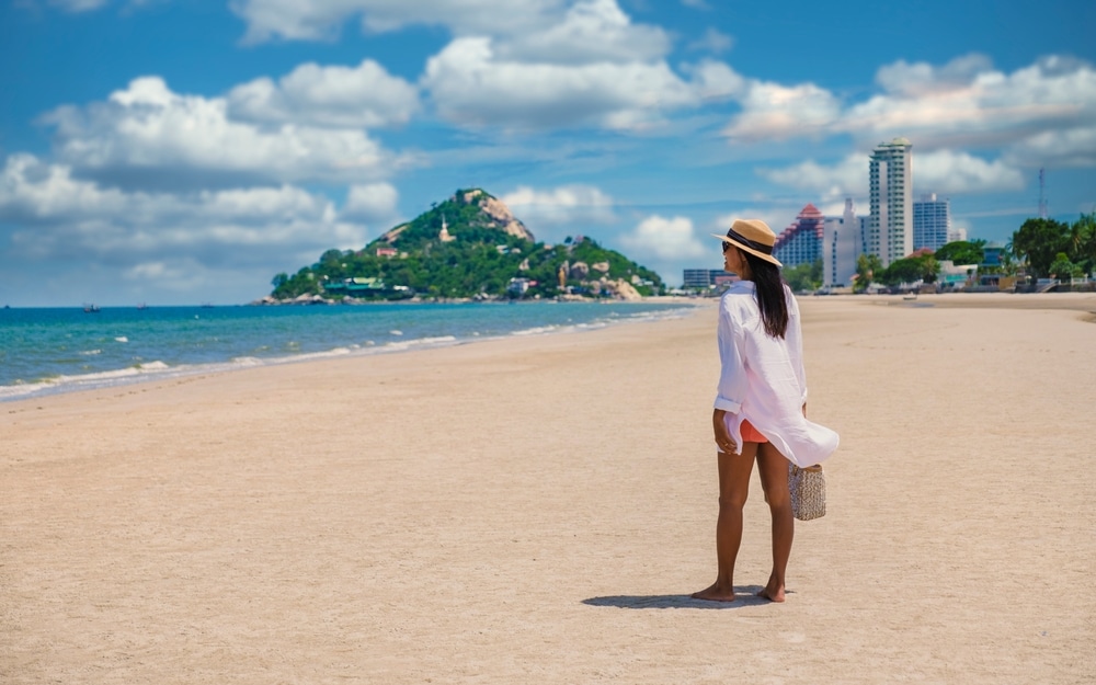 ผู้หญิงคนหนึ่งยืนอยู่บนชายหาดมองดูเมือง