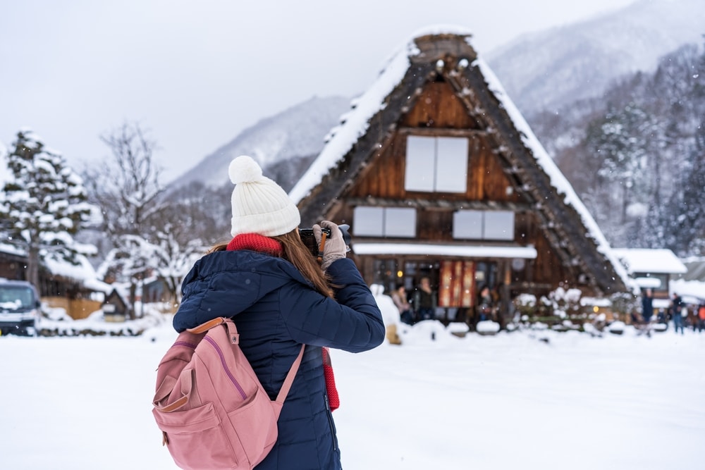 หญิงสาวกำลังจับบ้านไม้ท่ามกลางหิมะขณะเยือนราชบุรี เที่ยวญี่ปุ่น