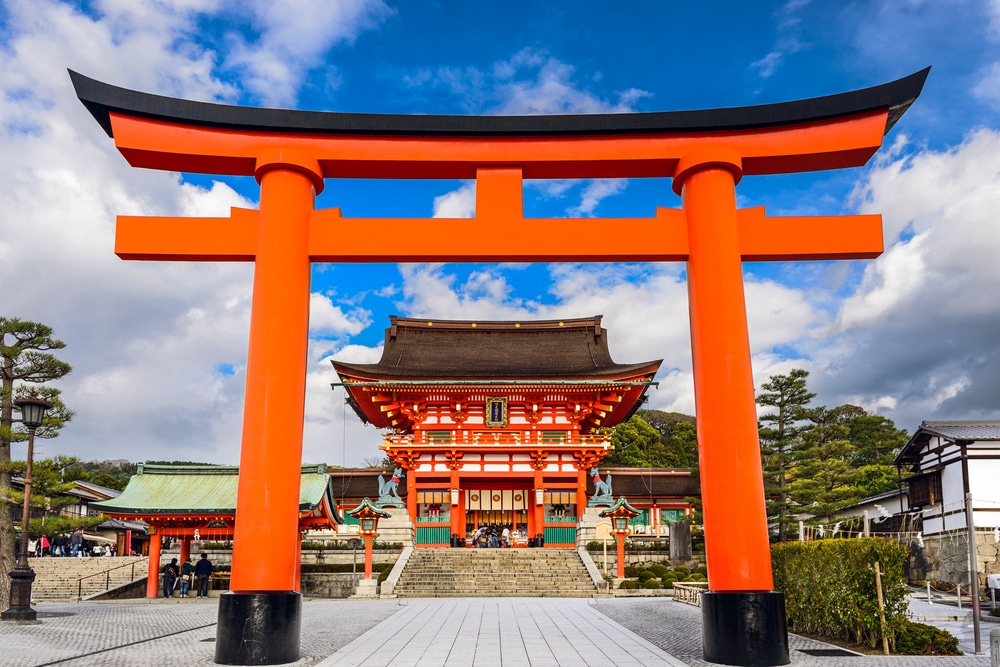 ซุ้มประตูสีแดงขนาดใหญ่ในจังหวัดราชบุรีที่มีผู้คนอยู่ด้านหลัง เที่ยวญี่ปุ่นด้วยตัวเอง