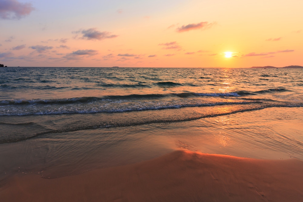 มีคนกำลังเดินอยู่บนชายหาดตอนพระอาทิตย์ตก เที่ยวทะเลใกล้กรุงเทพ