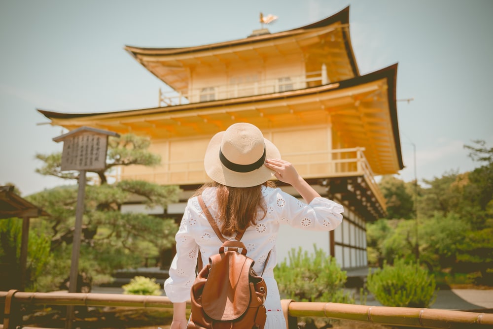 ผู้หญิงสวมหมวกและกระเป๋าเป้ยืนอยู่หน้าเจดีย์ทองในราชบุรีที่เที่ยว ที่เที่ยวญี่ปุ่น