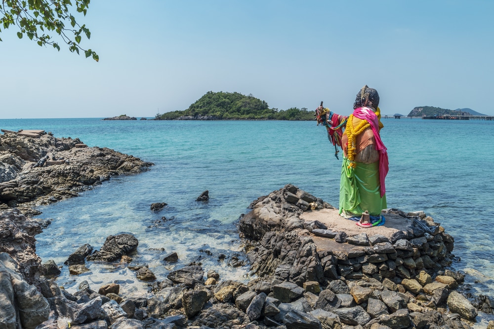 ผู้หญิงในชุดส่าหรีสีสันสดใสยืนอยู่บนโขดหินใกล้ทะเล เที่ยวทะเลใกล้กรุงเทพ