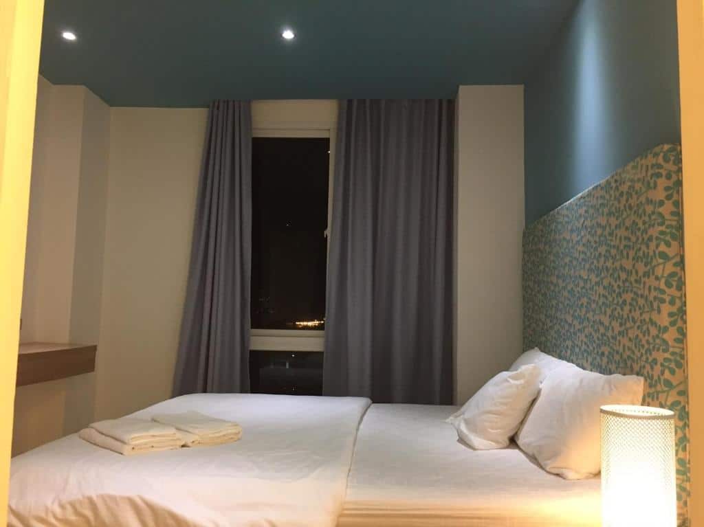 ห้องพักในโรงแรมที่จัดอย่างประณีตพร้อมเตียงคู่ ผ้าม่านเปิดออกสู่ทิวทัศน์ยามค่ำคืน และแสงไฟนวลๆ ที่หาดจอมเทียนติด โรงแรมหาดจอมเทียน