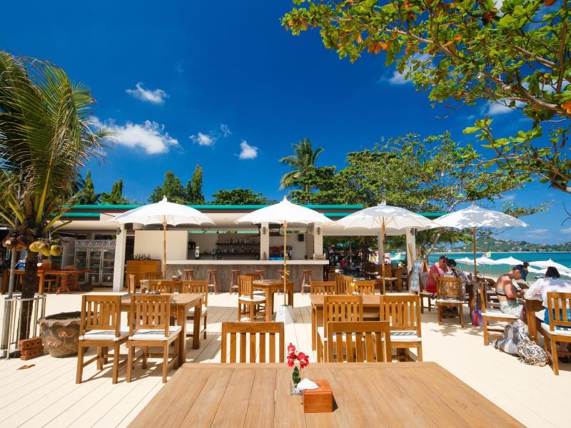 ร้านอาหารริมชายหาดพร้อมที่นั่งกลางแจ้งใต้ร่มสีขาวในวันที่แดดจ้า เที่ยวสมุย