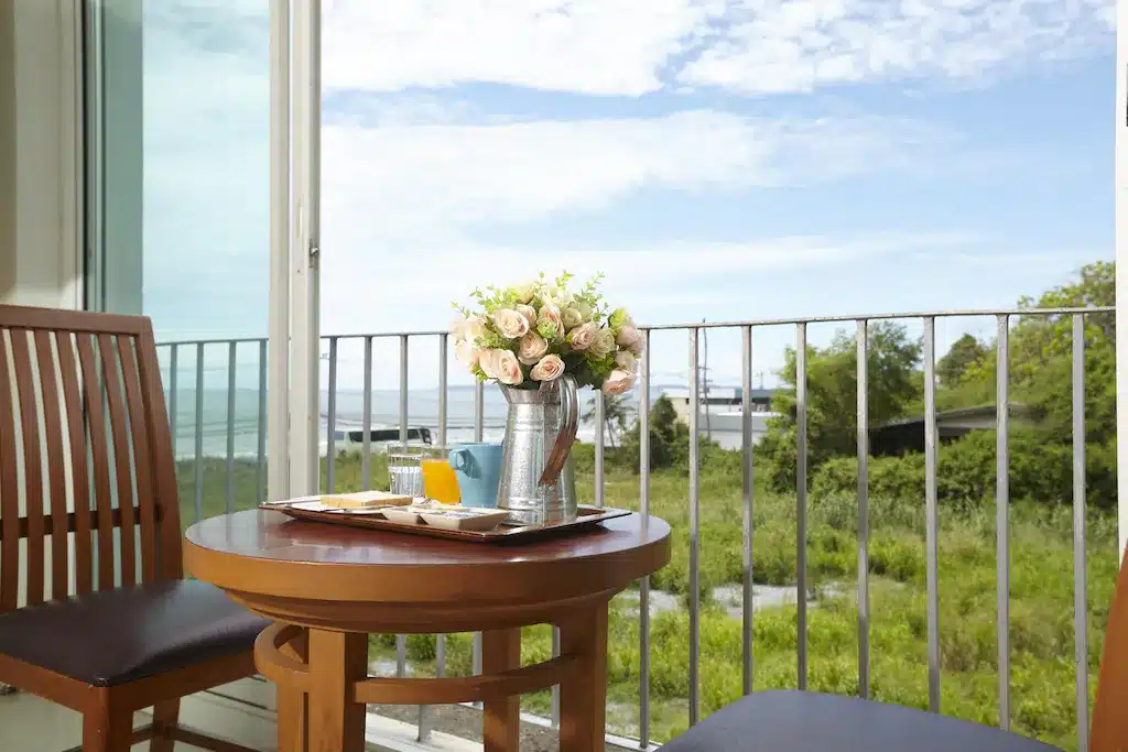 การตั้งค่าอาหารเช้าบนโต๊ะบนระเบียงที่โรงแรมหาดจอมเทียนพร้อมทิวทัศน์อันเขียวขจีและท้องฟ้า ที่พักหาดจอมเทียน