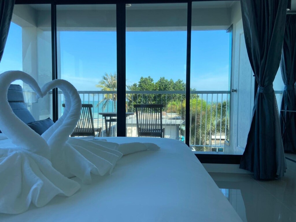 ห้องพักในโรงแรมที่มีผ้าขนหนูรูปหงส์จัดอยู่บนเตียง มองเห็นวิวระเบียงพร้อมวิวทะเล ที่เที่ยวขนอม