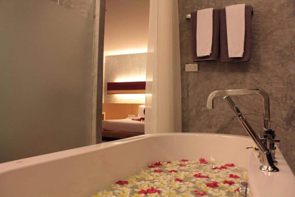 อ่างอาบน้ำที่เต็มไปด้วยน้ำและกลีบดอกไม้ในจอมเทียน หาดจอมเทียนที่พัก ติดกับห้องนอนที่มองเห็นได้จากทางเข้าประตู