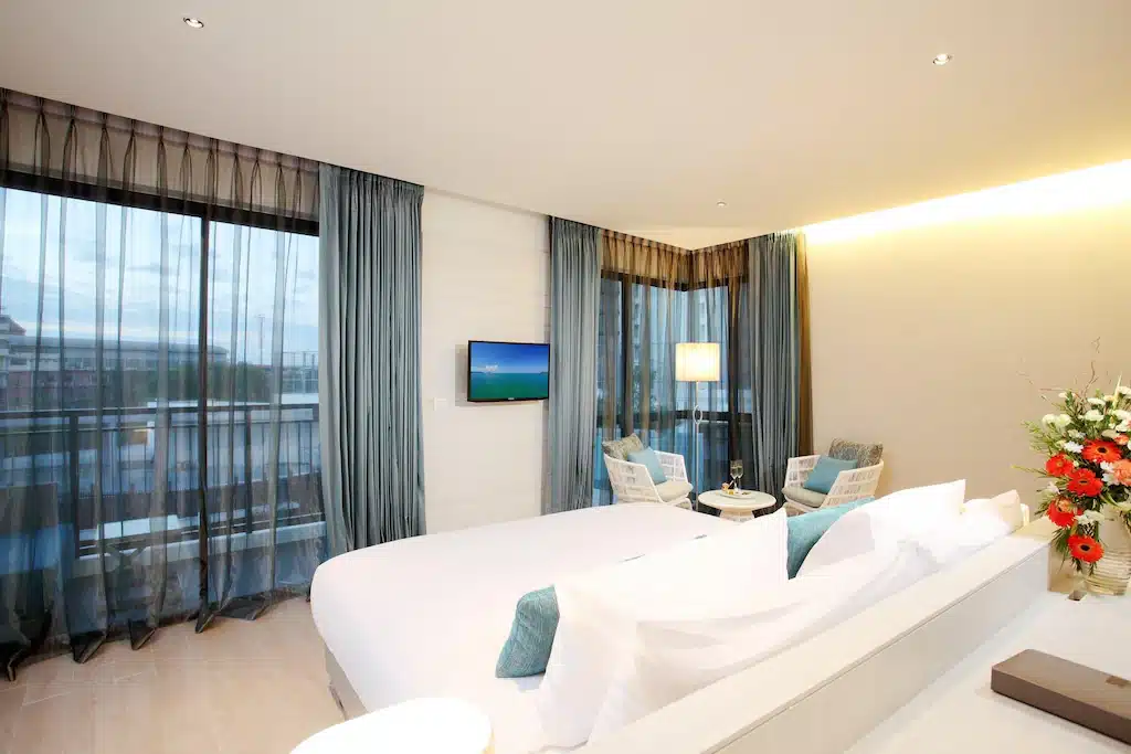 ห้องพักในโรงแรมทันสมัยพร้อมเตียงขนาดคิงไซส์ ทีวีจอแบน และวิวด้านนอกผ่านผ้าม่านที่หาดจอมเทียนติด ที่พักหาดจอมเทียน