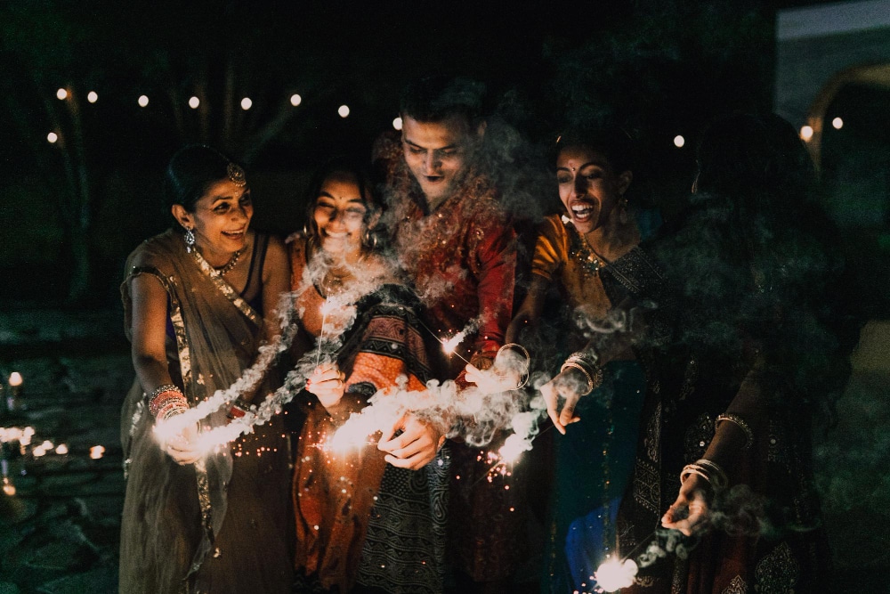 ครอบครัวชาวอินเดียกำลังเล่นดอกไม้ไฟในงานเฉลิมฉลองยามค่ำคืนอย่างสนุกสนาน