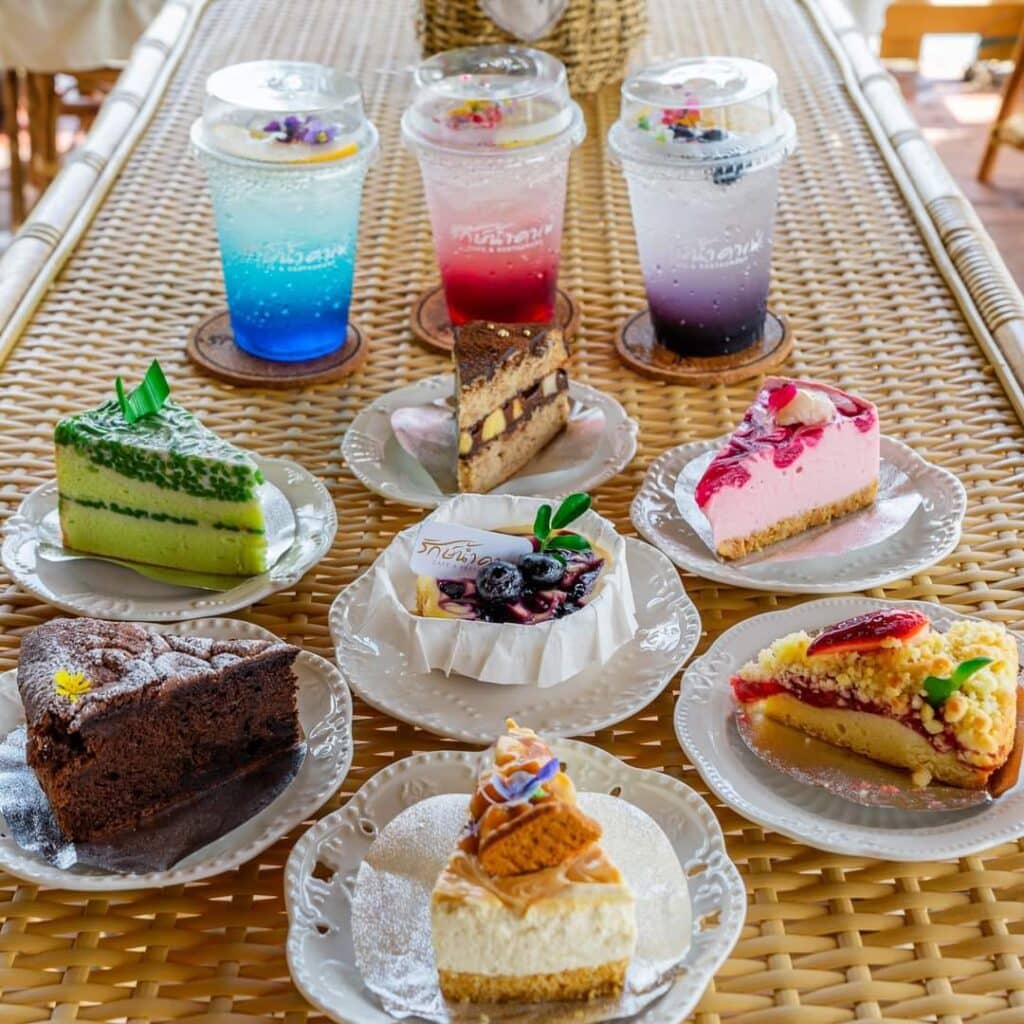 เครื่องดื่มหลากสีสันและเค้กชิ้นต่างๆ บนโต๊ะทอ ในนครปฐมที่เที่ยวธรรมชาติ นครปฐมที่เที่ยวธรรมชาติ