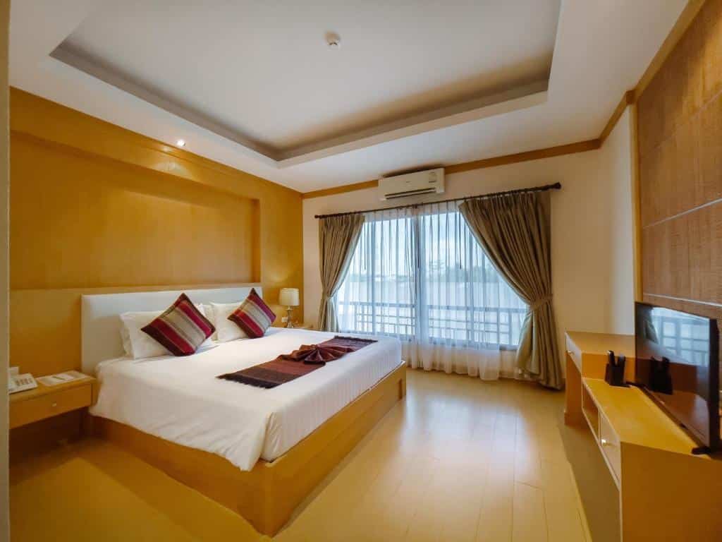 ห้องพักในโรงแรมที่จัดอย่างประณีตพร้อมเตียงขนาดใหญ่ หัวเตียงไม้ และโทรทัศน์บนตู้ ตกแต่งแบบ บั้งไฟพญานาค