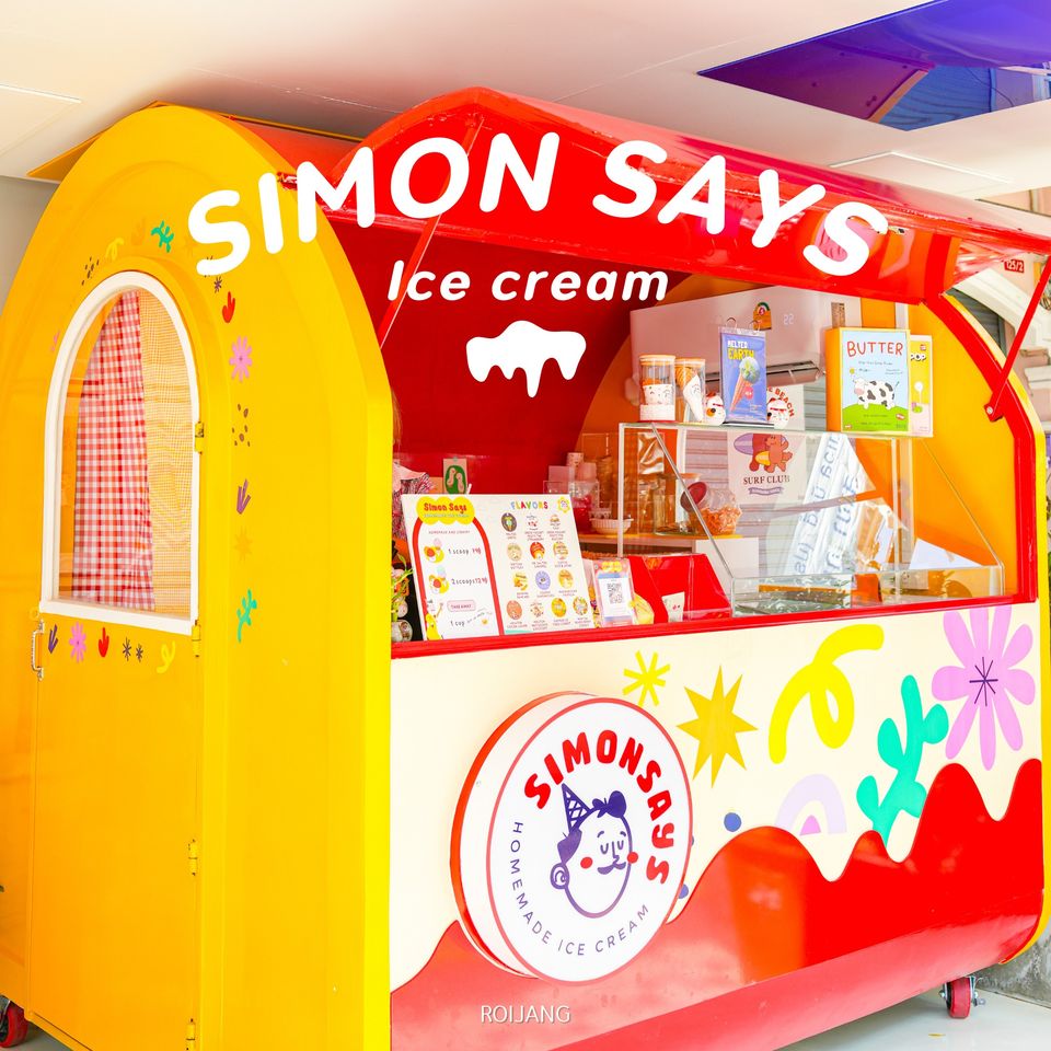 รถเข็นไอศกรีมหลากสีสันมีแบรนด์ "simon says ice cream" จัดแสดงอยู่ด้านข้าง จอดอยู่ที่ ถนนคนเดินภูเก็ต