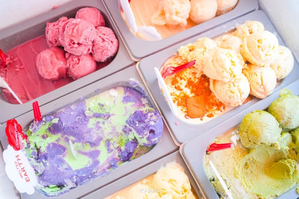ไอศกรีมหลากหลายรสชาติที่จัดแสดงพร้อมสกูปและฉลากรสชาติที่ ถนนคนเดินภูเก็ต