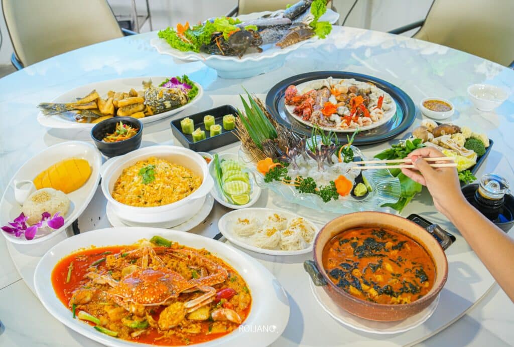 อาหารเอเชียหลากหลายชนิดกระจายอยู่บนโต๊ะที่ร้านอาหารทะเลในภูเก็ต ร้านอาหารภูเก็ต