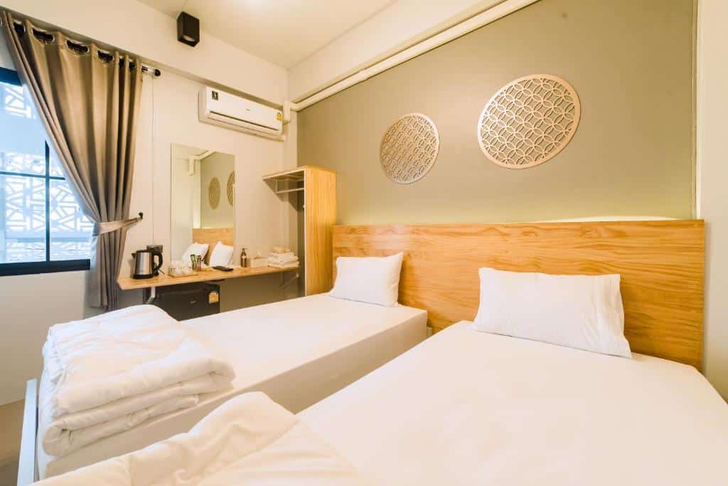 ห้องพักในโรงแรมที่สะอาดและเรียบง่ายพร้อมเตียงเดี่ยว 2 เตียง ชุดเครื่องนอนสีขาว และการตกแต่งแบบเรียบง่าย โรงแรมในเบตง