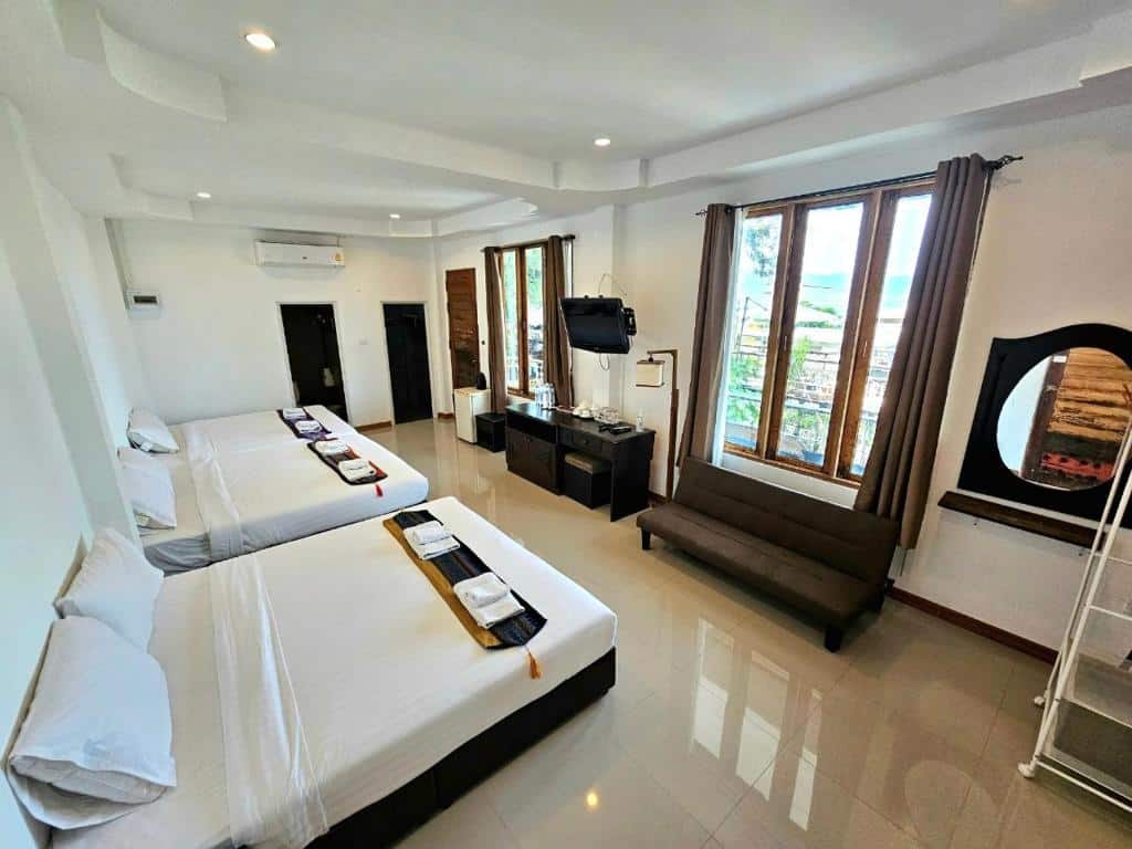 ห้องพักในโรงแรมสว่างและกว้างขวางในทับน มีเตียงขนาดใหญ่ โซฟา ที่พักเกาะแสมสาร และหน้าต่างที่มองเห็นวิว