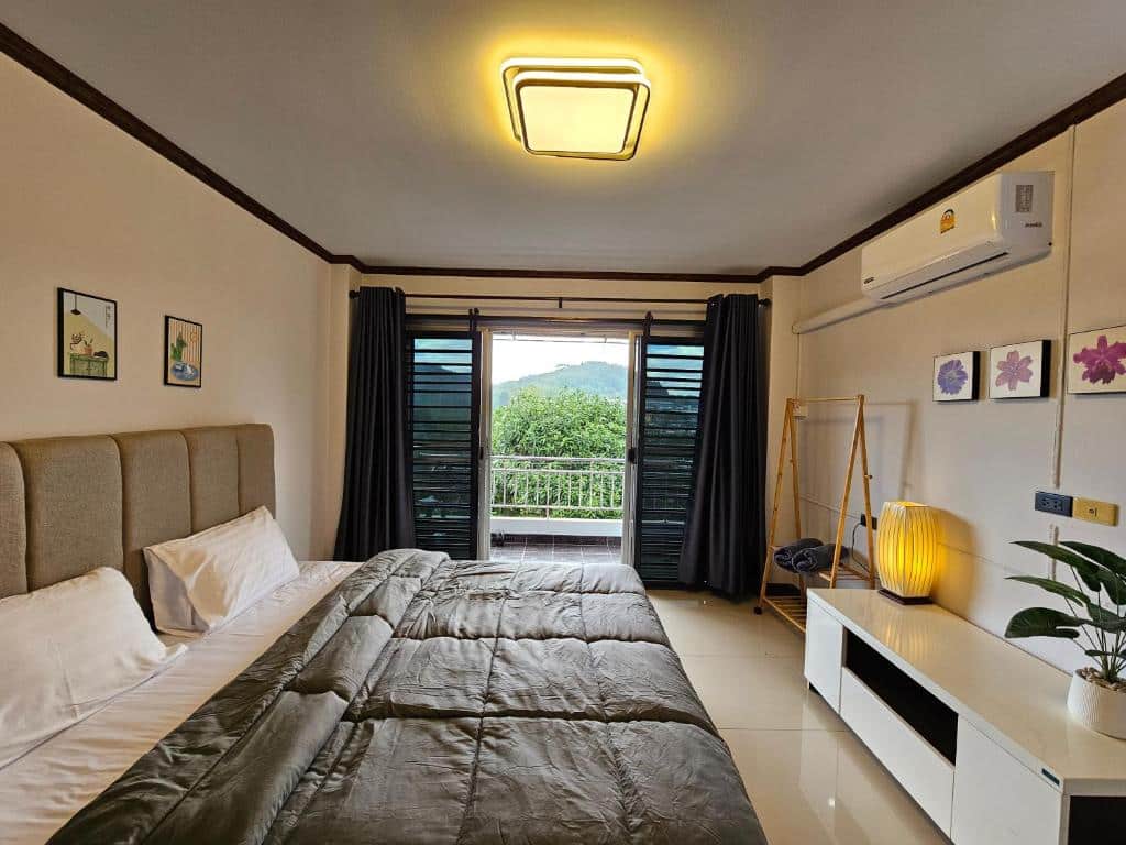 ห้องนอนทันสมัยพร้อมเตียงขนาดใหญ่ ผ้าม่านสีเข้ม และทิวทัศน์อันเขียวขจีด้านนอกโรงแรมในเบตง