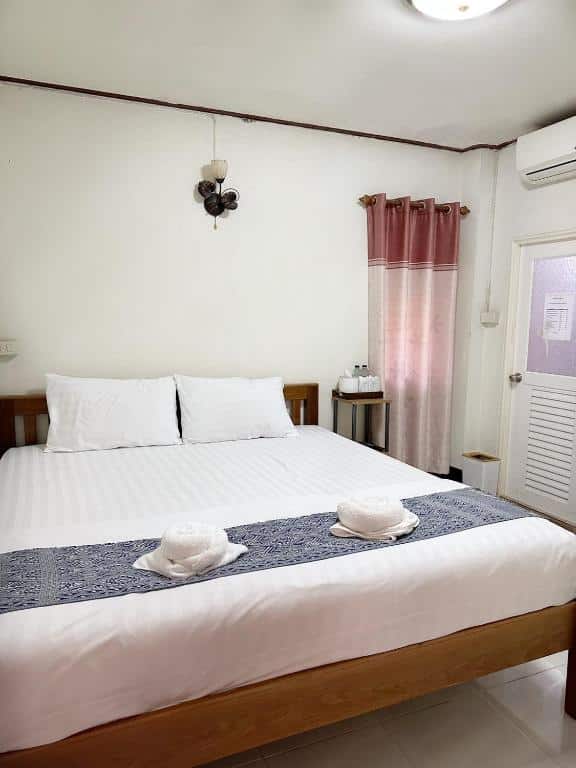 ห้องนอนที่จัดอย่างประณีตพร้อมเตียงขนาดใหญ่ ผ้าปูเตียงสีขาว และผ้าปูเตียงสีน้ำเงิน เสริมด้วยการตกแต่งแบบเรียบง่ายและพัดลมเพดาน ที่พักเชียงคานใกล้ถนนคนเดิน มอบความสะดวกสบายเชในอุดมคติ