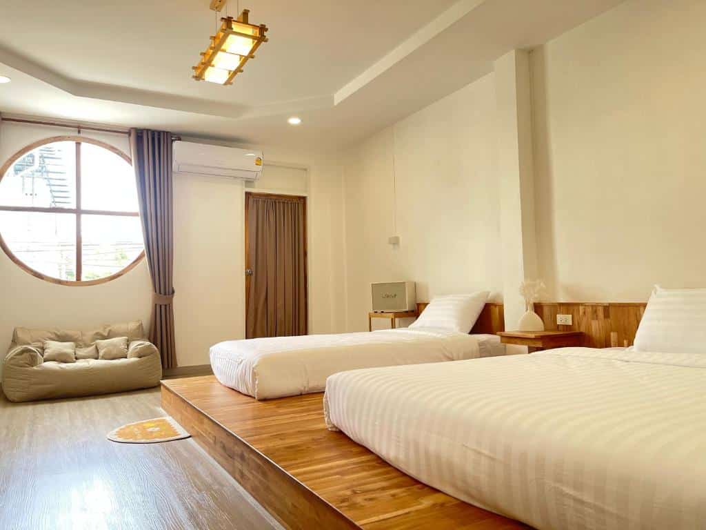 ห้องพักในโรงแรมที่สว่างสดใสและสะดวกสบายมีเตียง 2 เตียง หน้าต่างทรงกลม และพื้นที่นั่งเล่น ที่พักเบตง