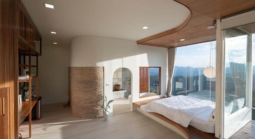 ห้องนอนที่มีหน้าต่างบานใหญ่มองเห็นวิวภูเขา ที่เที่ยวแม่ริม
