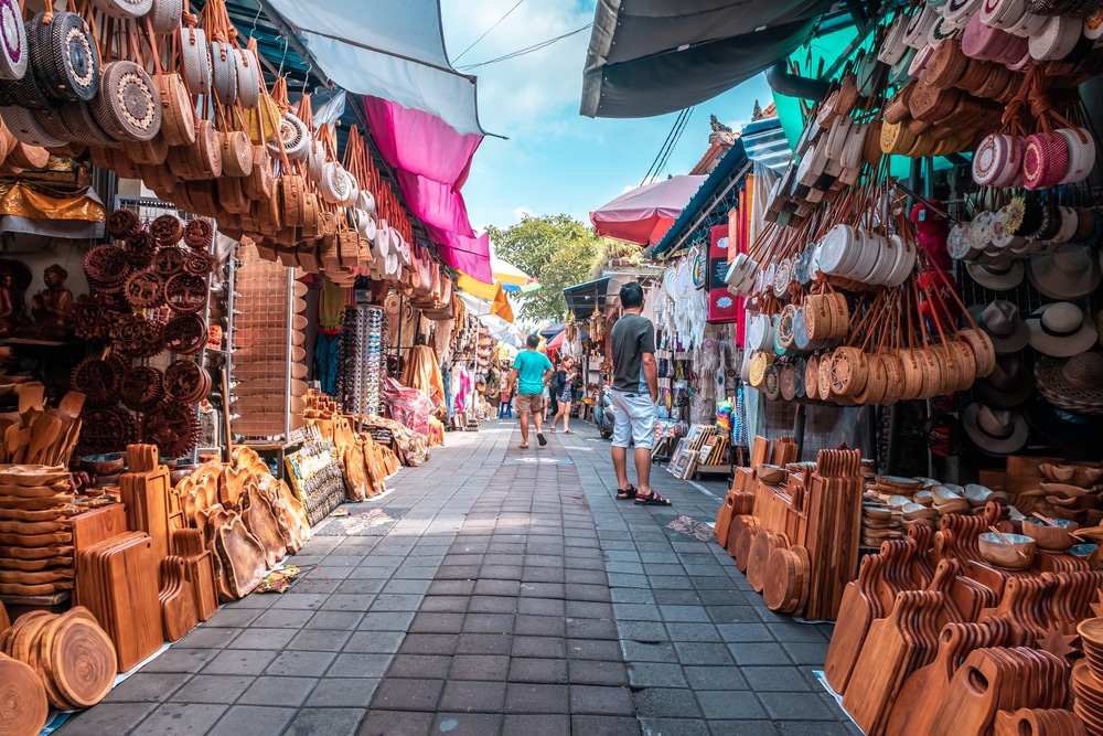 ถนนตลาดอันคึกคักในราชบุรี เรียงรายไปด้วยแผงขายงานฝีมือและสินค้าที่ทำจากไม้มากมาย คึกคักไปด้วยนักช้อปใต้ท้องฟ้าสดใส ที่เที่ยวบาหลี