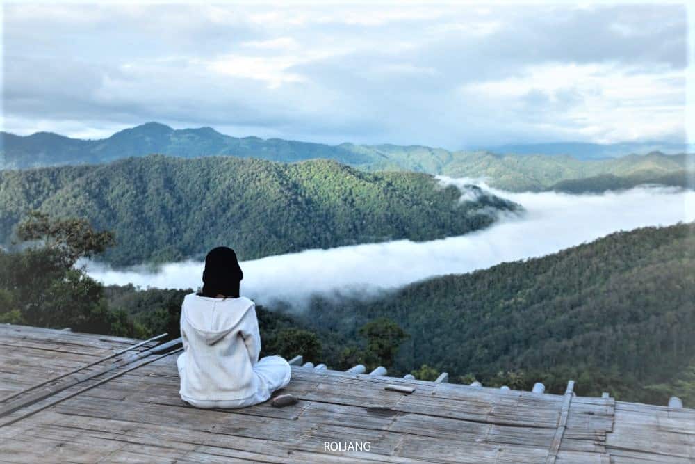 คนที่นั่งบนพื้นไม้มองดูภูเขาที่มีเมฆลอยต่ำในเวลาเช้าหรือค่ำทำให้รู้สึกสงบที่เที่ยวเดือนพ ที่เที่ยวเดือนพฤศจิกายน ฤ