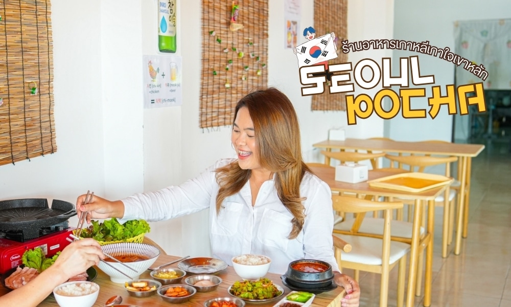 ผู้หญิงกำลังเพลิดเพลินกับอาหารเกาหลีที่ร้านเขาหลัก โดยมีอาหารหลากหลายอยู่บนโต๊ะ ร้านอาหารเขาหลัก