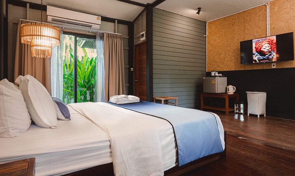 ห้องพักในโรงแรมแสนสบายพร้อมเตียงขนาดใหญ่ สิ่งอำนวยความสะดวกทันสมัย และวิวแมกไม้เขียวขจีนอกหน้าต่าง ที่เที่ยวขนอม