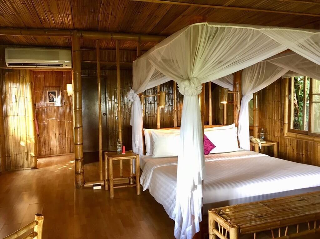 ห้องนอนพร้อมเตียงสี่เสาในห้องไม้ที่รีสอร์ทบนภูเขาเชียงราย ที่พักเชียงรายบนดอย