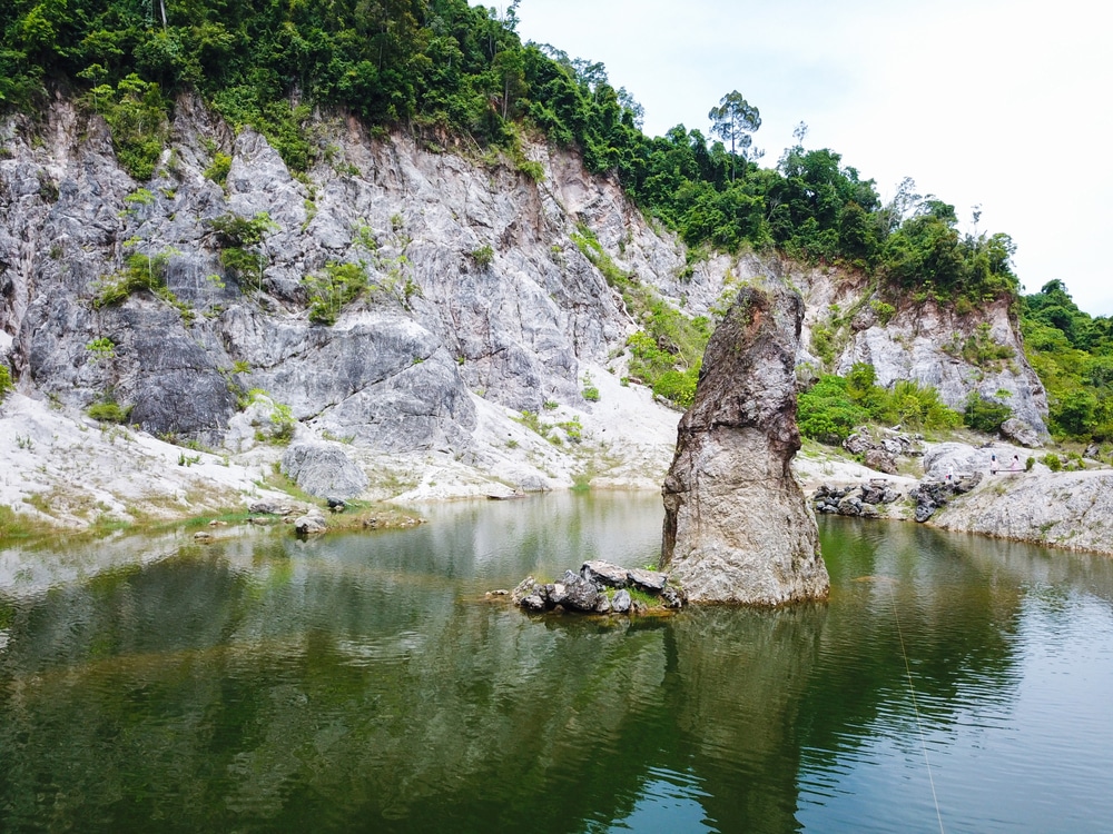 กลุ่มหินปูนที่โผล่ขึ้นมาจากทะเลสาบอันเงียบสงบโดยมีหน้าผาหินเป็นฉากหลัง ที่เที่ยวขนอม