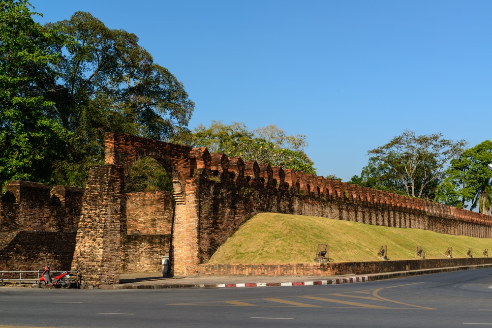 กำแพงอิฐโบราณที่มีลูกเมอร์ลอนอยู่ตามถนนในเมือง ใต้ท้องฟ้าสีครามสดใส ที่เที่ยวนครศรีธรรมราช