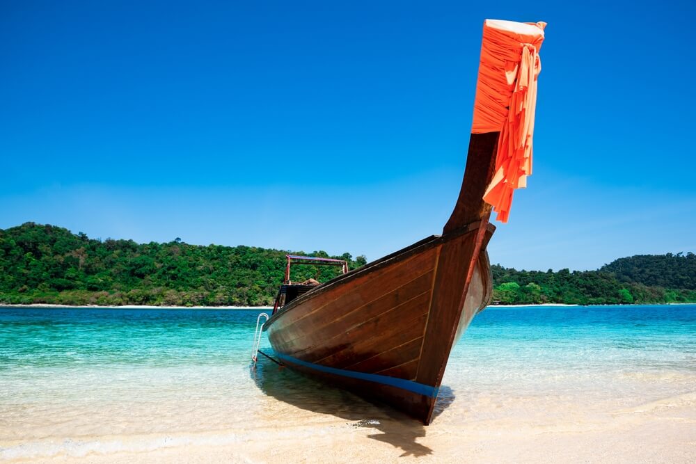 เรือลำหนึ่งจอดอยู่บนหาดทรายของเกาะกระบี่ เกาะกระบี่ ที่เที่ยวเดือนพฤศจิกายน