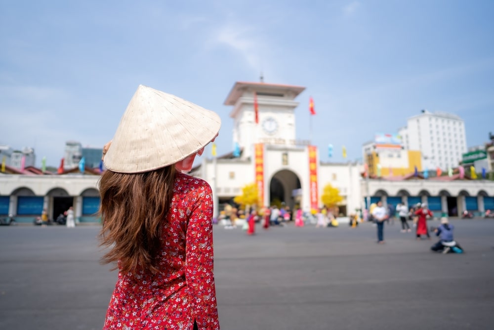 ผู้หญิงสวมหมวกทรงกรวยกำลังมองตลาด Ben Thanh ซึ่งเป็นสถานที่เที่ยว โฮจิมินห์ที่เที่ยว ในโฮจิมินห์ซิตี้