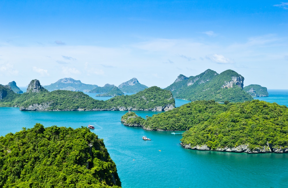 หมู่เกาะเขตร้อนที่มีเกาะสีเขียวชอุ่มและน้ำทะเลสีฟ้าคราม มีเรือแล่นไปตามอ่าวอันงดงาม ที่เที่ยวเกาะสมุย