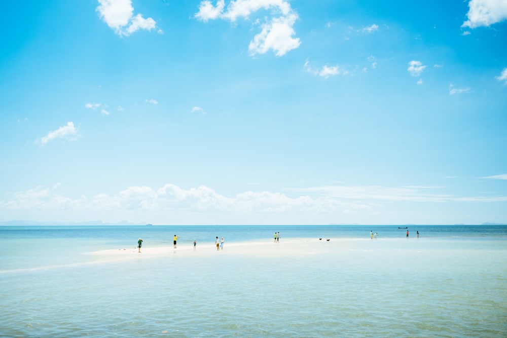ผู้คนลุยน้ำตื้นที่ชายหาดอันเงียบสงบในวันที่แดดจ้า เที่ยวเกาะสมุย