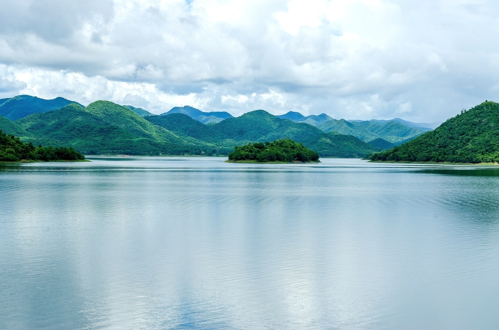 ทะเลสาบอันเงียบสงบที่ล้อมรอบด้วยเนินเขาสีเขียวชอุ่มใต้ท้องฟ้าที่มีเมฆมาก เหมาะสำหรับการท่องเที่ยวเดือนเมษายน ที่เที่ยวเดือนเมษายน