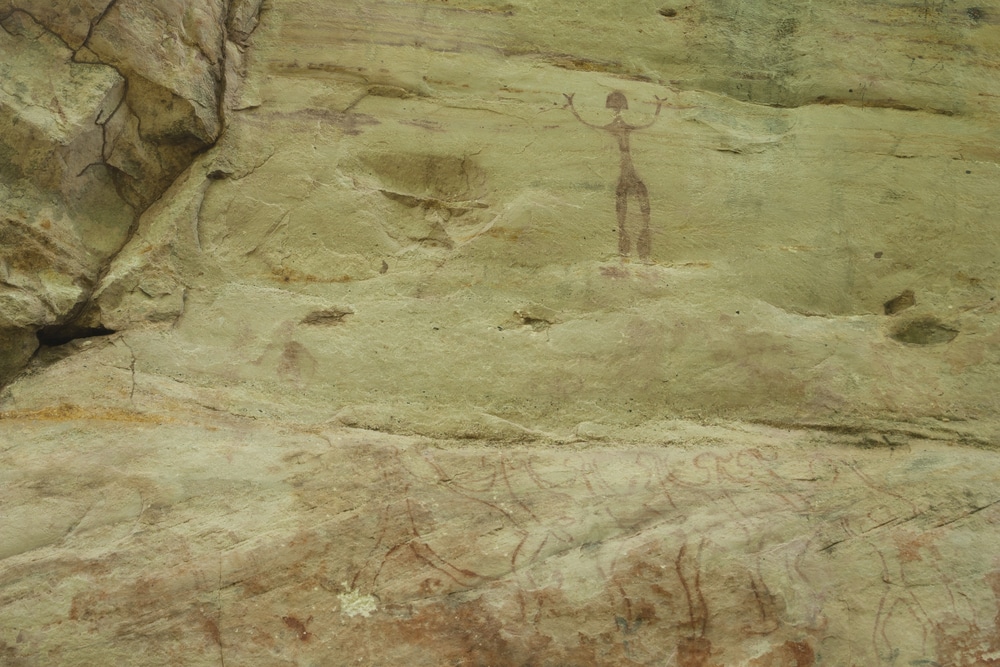 ศิลปะหินโบราณที่แสดงภาพมนุษย์และสัญลักษณ์บนพื้นผิวหินที่ผุกร่อน เที่ยวสกลนคร
