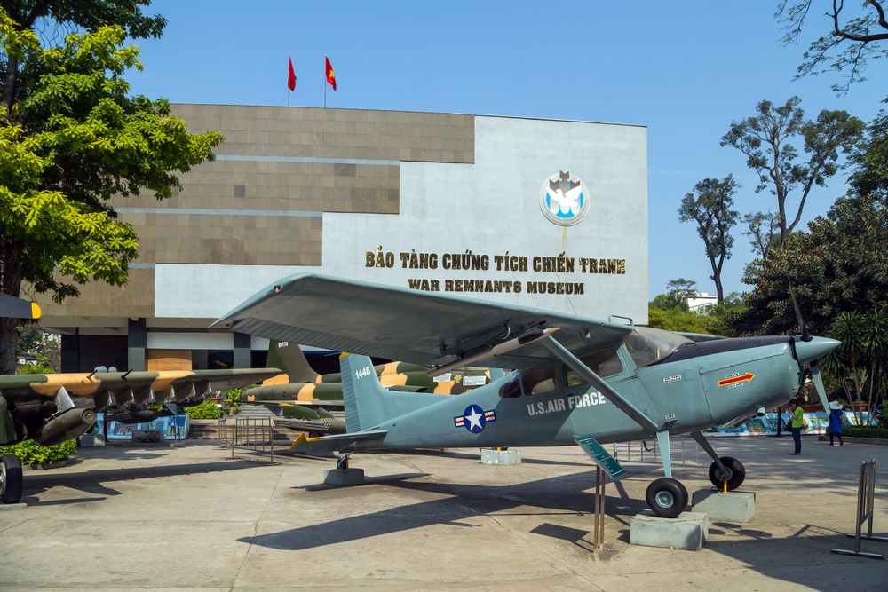 เครื่องบินของกองทัพอากาศสหรัฐฯ จัดแสดงหน้าพิพิธภัณฑ์เศษซากสงครามในเมืองโฮจิมินห์ ประเทศเวียดนาม พร้อมข้อความภาษาเวียดนามว่า 'báo tàng chứng tích chiến  โฮจิมินห์ที่เที่ยว tranh'