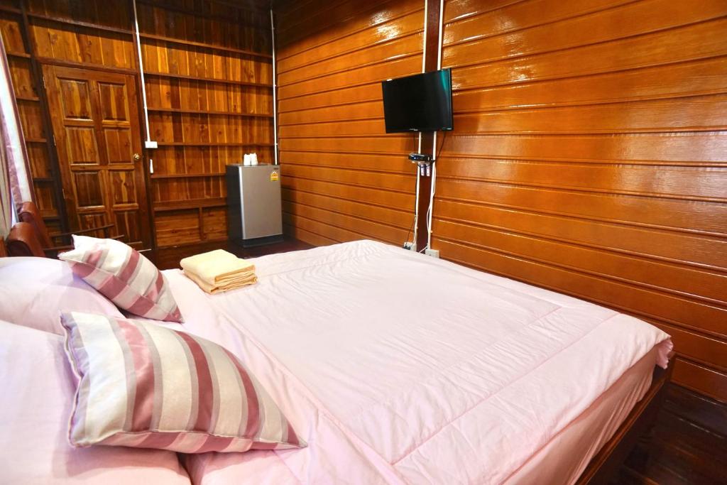 ห้องนอนที่เป็นระเบียบเรียบร้อยพร้อมเตียงคู่ ผนังไม้ และโทรทัศน์ติดผนัง มอบประสบการณ์ที่สมบูรณ์แบบใกล้กรุงเทพ ที่พักใกล้กรุงเทพ