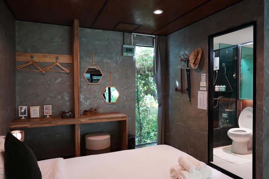 ห้องพักทันสมัยใกล้กรุงเทพพร้อมวิวห้องน้ำที่อยู่ติดกันและต้นไม้เขียวขจีที่มองเห็นได้ผ่านหน้าต่าง ที่พักใกล้กรุงเทพ