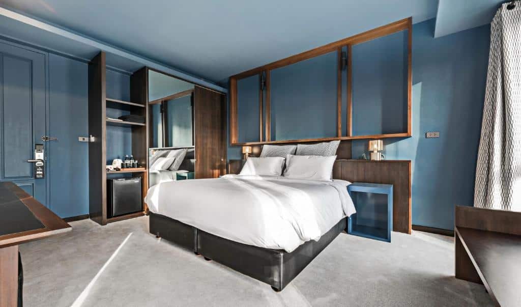ห้องนอนทันสมัยพร้อมเตียงขนาดใหญ่ ผนังสีฟ้า ชั้นวางของไม้ และการตกแต่งที่หรูหราในที่พักหัวหิน โรงแรมหัวหิน