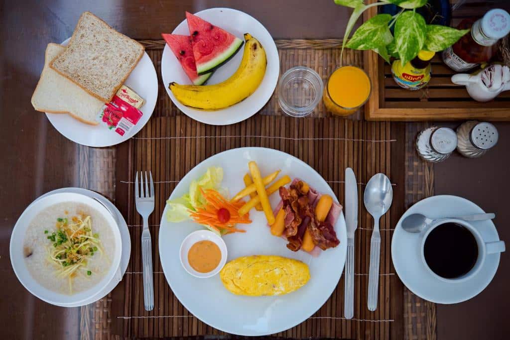 การจัดโต๊ะอาหารเช้าที่โรงแรมหัวหิน พร้อมด้วยจานไข่ เบคอน มันฝรั่งทอด สลัด ผลไม้ชิ้น ซุป ขนมปังปิ้ง น้ำส้ม  ที่พักหัวหิน