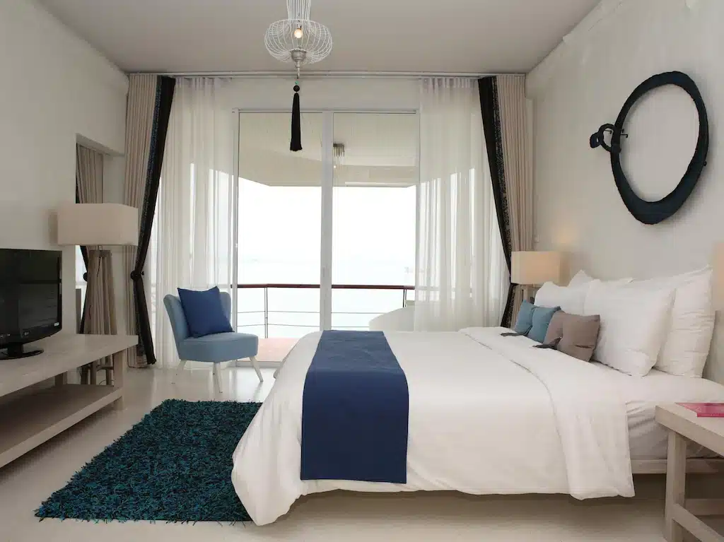 ห้องนอนทันสมัยพร้อมเตียงขนาดใหญ่ ตกแต่งสีขาวและสีฟ้าที่บลูสกายรีสอร์ทเกาะพยาม และระเบียงที่มองเห็นวิว ที่พักเกาะพยาม