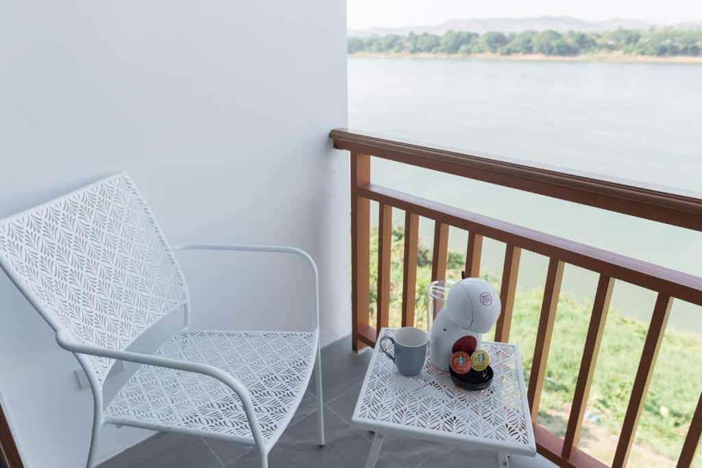 เก้าอี้สองตัวและโต๊ะเล็กพร้อมเครื่องชงกาแฟและแก้วน้ำบนร ที่พักเชียงคานติดริมโขง ะเบียงที่มองเห็นแม่น้ำโขงในเชียงคาน