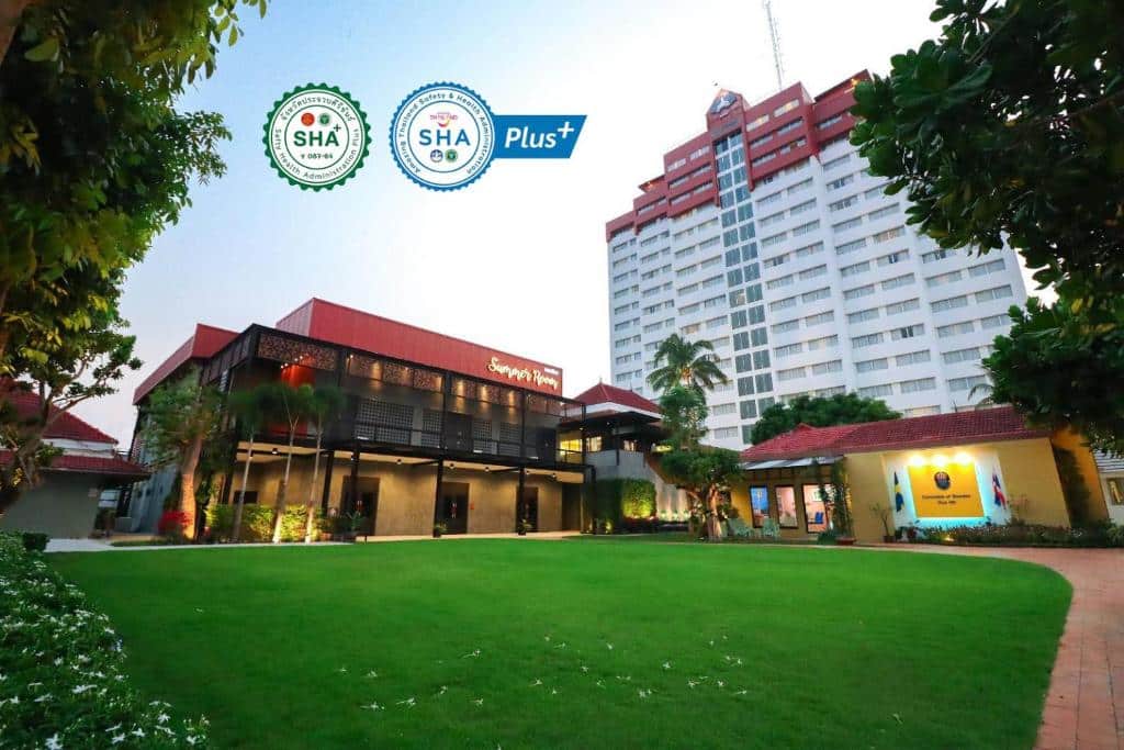 อาคารทรงไทยดั้งเดิมหน้าโรงแรมสูงทันสมัยในหัวหิน ล้อมรอบด้วยสวนเขียวชอุ่มและท้องฟ้าสีครามสดใส โรงแรมหัวหิน