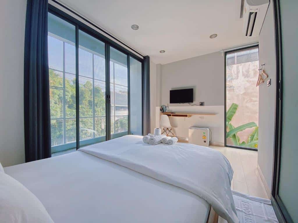 ห้องพักในโรงแรมทันสมัย มีเตียงคู่ที่ตกแต่งอย่างประณีต ทีวีติดผนัง และหน้าต่างบานใหญ่ที่มองเห็นวิวภายนอกที่เขียวขจี ที่เที่ยวเบตง