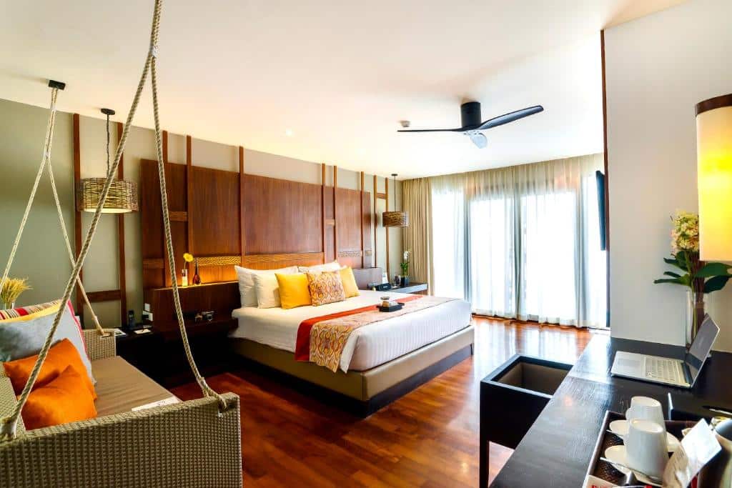 ห้องพักในโรงแรมสว่างสดใสในหัวหินที่มีเตียงขนาดใหญ่พร้อมหมอนสีสันสดใส เก้าอี้หวายแขวน และพื้นไม้  ที่พักหัวหิน