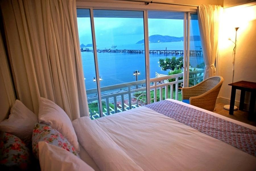 ภายในห้องพักโรงแรมมีเตียง มองออกไประเบียง เห็นวิวทะเลและภูเขาช่วงพลบค่ำ ที่หาดเตยงามที่พักติ หาดเตยงามที่พัก